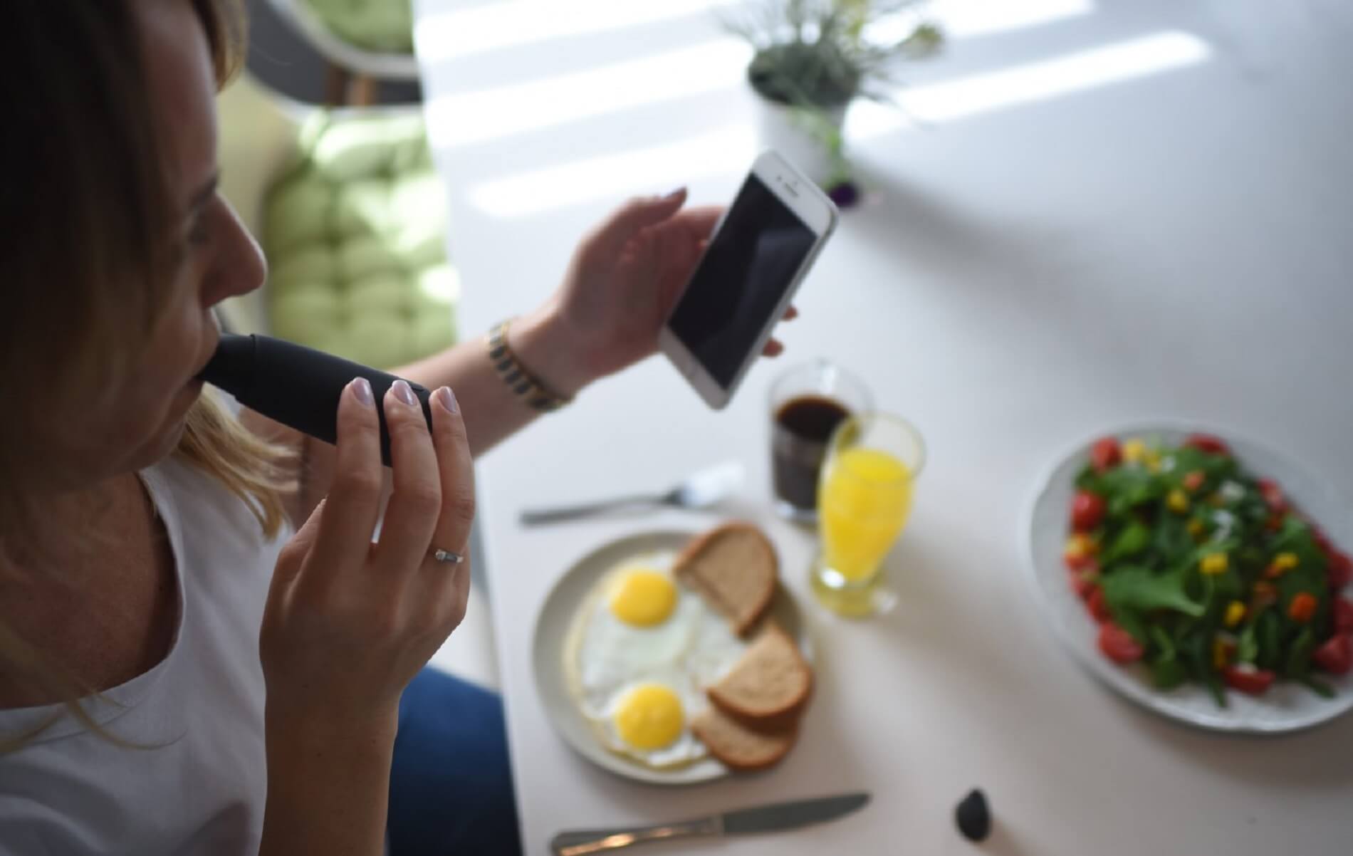 Science - A woman sits at a dining table and blows into Lumen's device